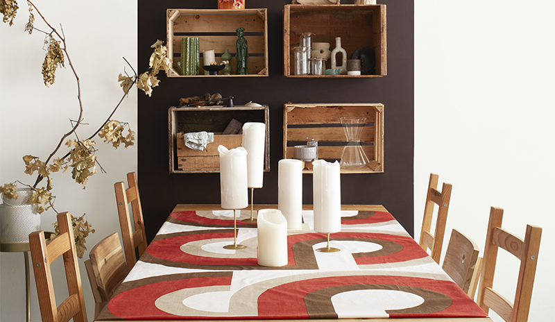 Modern apartment dining area: dark brown accent panel, wood table/chairs, crate shelves, orange/brow