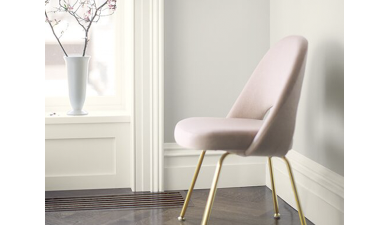 Una silla rosa enmarca una pared pintada en Balboa Mist OC-27.